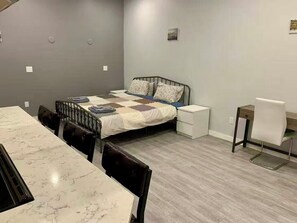 A bedroom with a bed, bedside tables, a desk, and a chair. - Cozy suite in Royal Oak (Victoria)