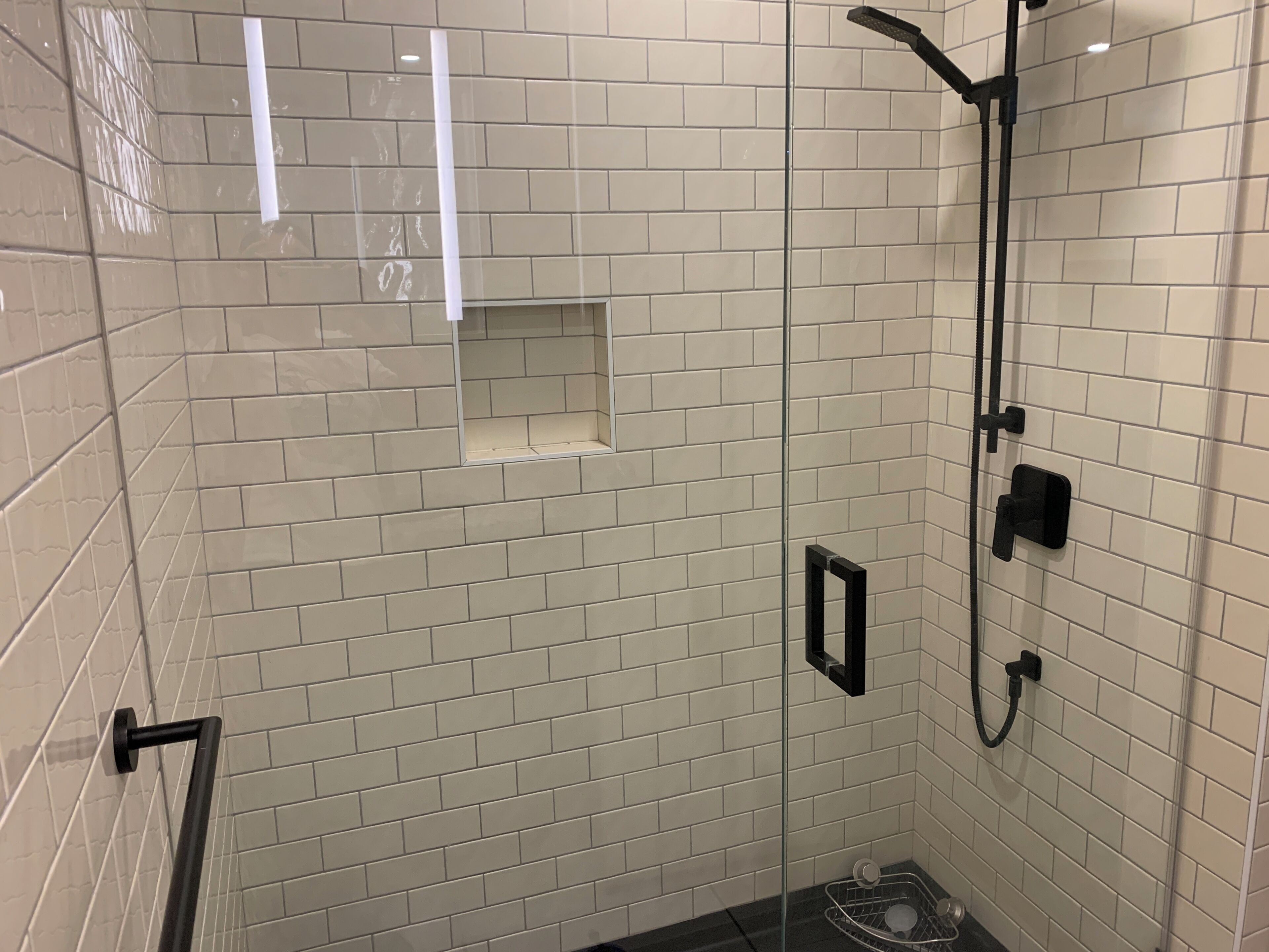 Ducha con puerta de vidrio, cabezal de ducha de mano y extensión de ducha manual.