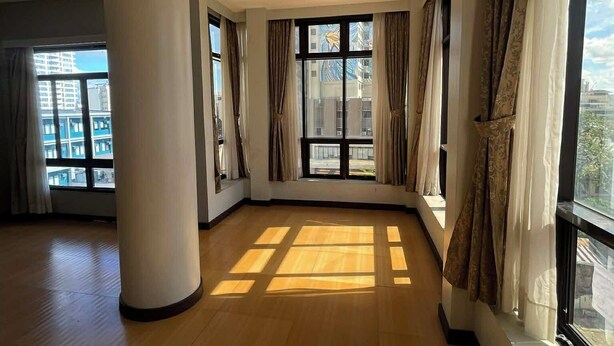 A spacious room with large windows, a wooden floor, and a central pillar. - Fuente Oro Business Suites (Cebu City)