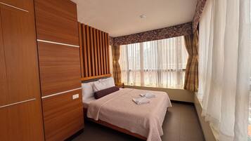 Un dormitorio con cama, armario de madera y ventana con cortinas.