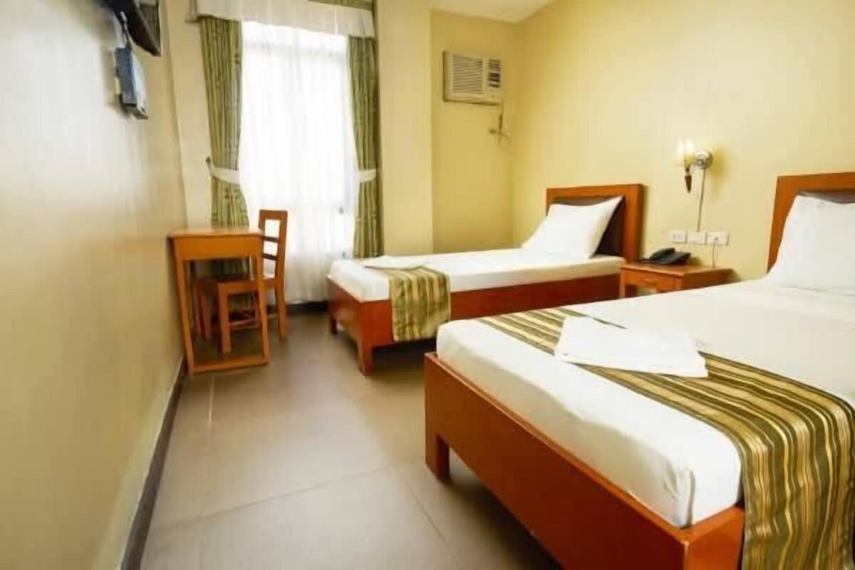 Habitación de hotel con dos camas individuales, un escritorio y una silla.