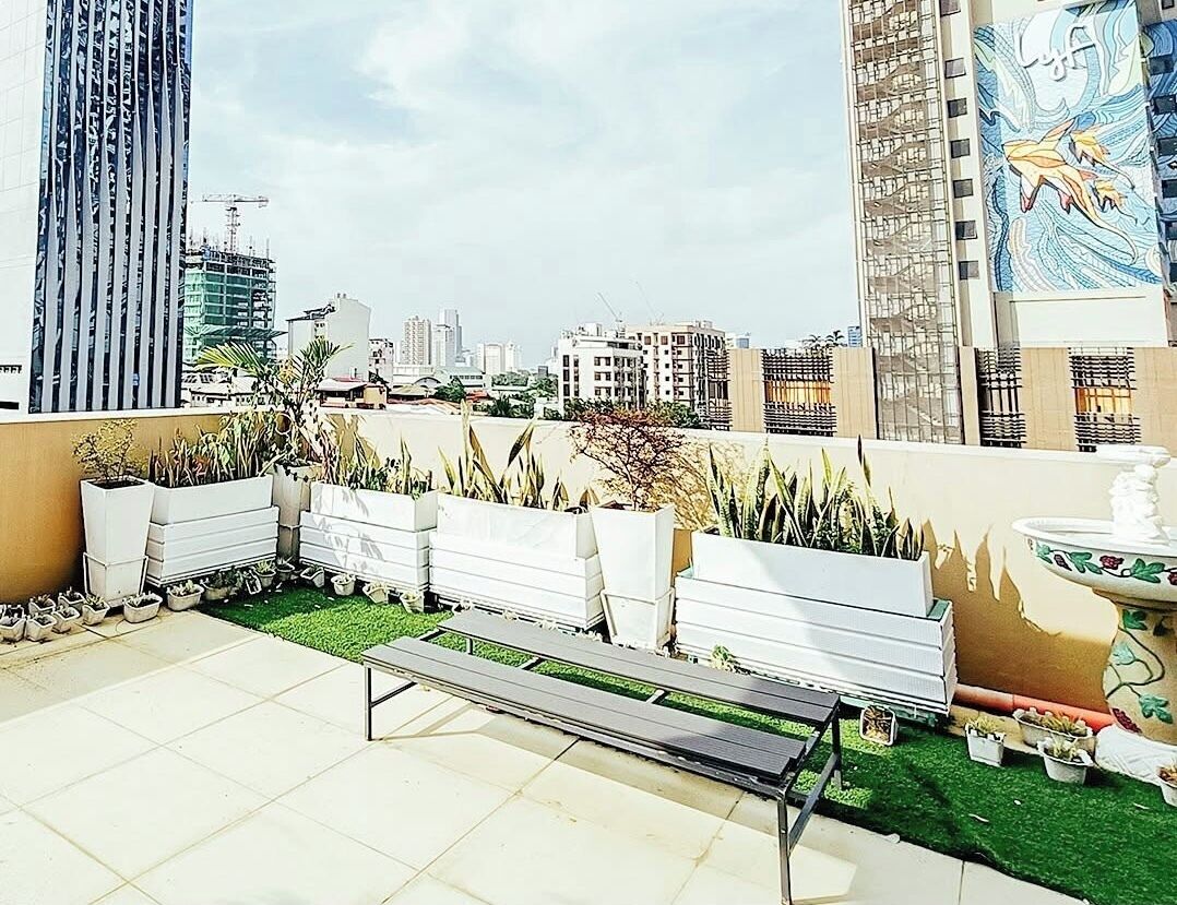 Una terraza en la azotea con macetas, un banco y una fuente.