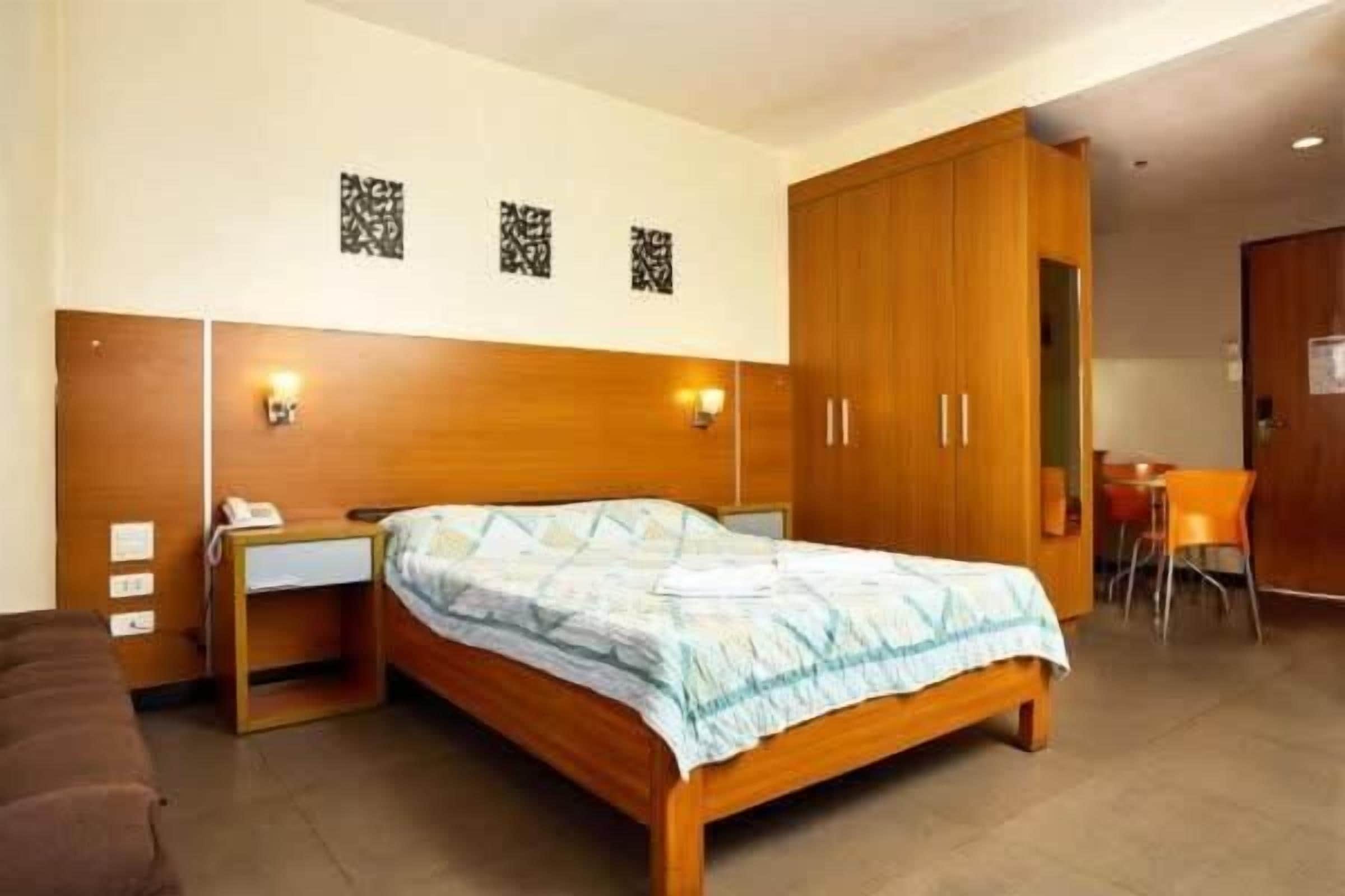 A bedroom with a wooden bed, bedside tables, a wardrobe, and a small desk with a chair.