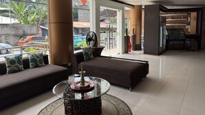 A modern hotel lobby with a sofa, a glass coffee table, and a view of the street outside. - Fuente Oro Business Suites (Cebu City)