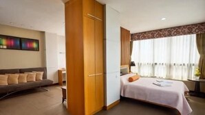 Una habitación con cama, sofá, armario y ventana con cortinas.