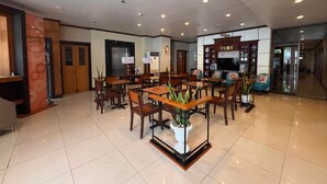 A hotel lobby with a reception desk, seating area, and a TV screen. - Fuente Oro Business Suites (Cebu City)