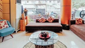 Un vestíbulo moderno con una mesa de centro redonda de vidrio, un sofá y un sillón azul.