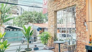 Un balcón con plantas en macetas, mobiliario exterior y un muro de piedra.