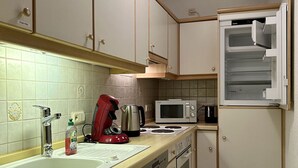 A compact kitchen with a sink, stove, microwave, and a refrigerator. - Cozy vacation apartment with balcony - 2 bedrooms with 2 private bathrooms (Erden)