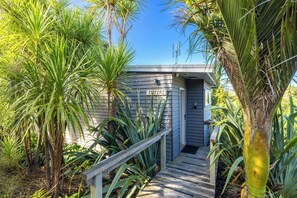 A pathway leading to a small building labeled 'TUTIRI' surrounded by tropical plants. - Tutiri – Oneroa Studio Retreat (Waiheke Island)