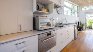 Una cucina moderna con mobili bianchi, elettrodomestici in acciaio inossidabile e un'ampia finestra che offre luce naturale.