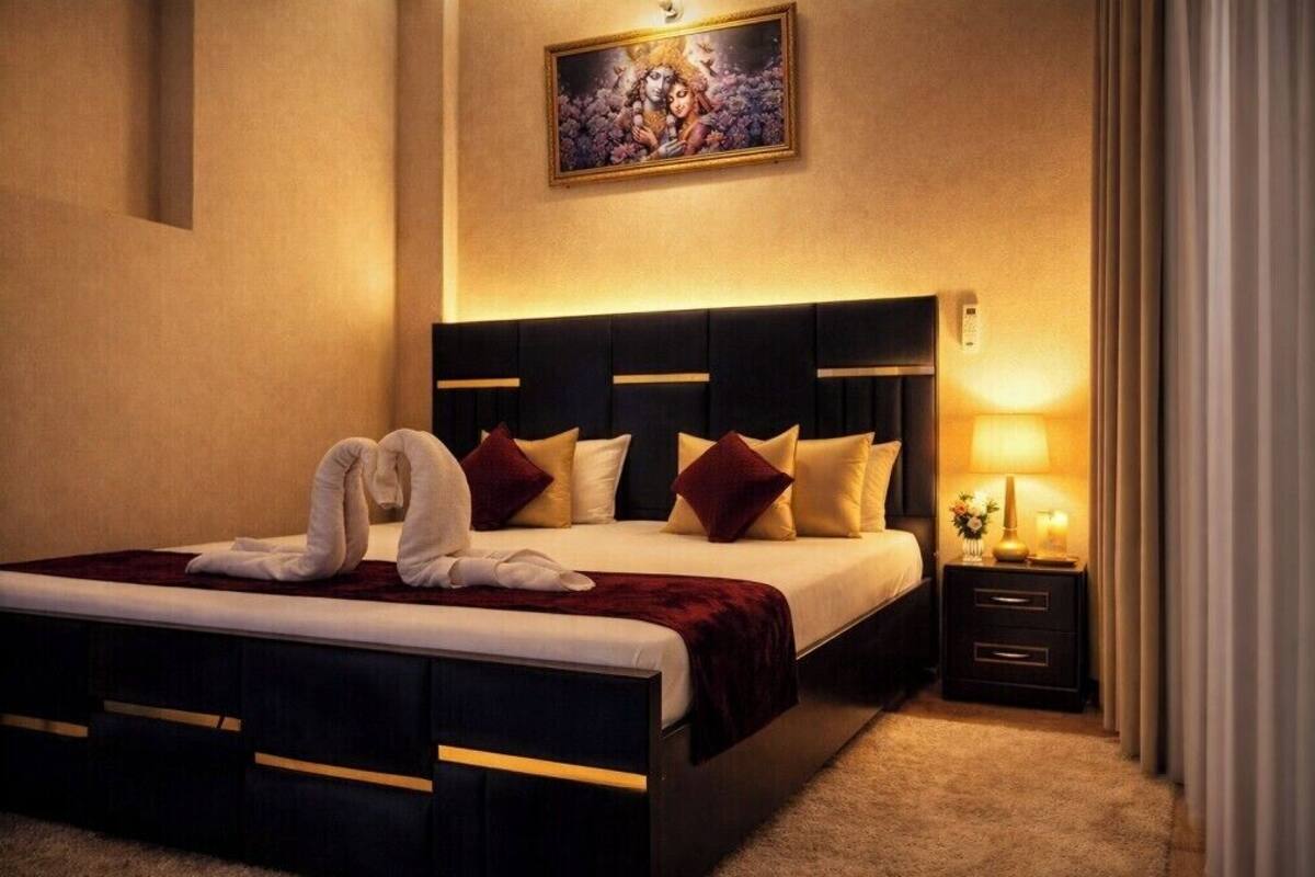 Una habitación de hotel con una cama grande, una mesita de noche con lámpara y un cuadro en la pared.
