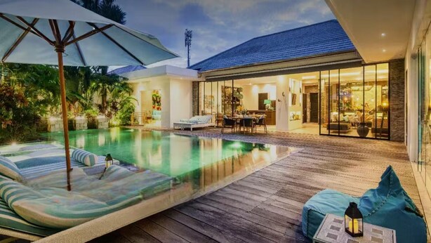 Een modern huis met een zwembad, terras en een serre.