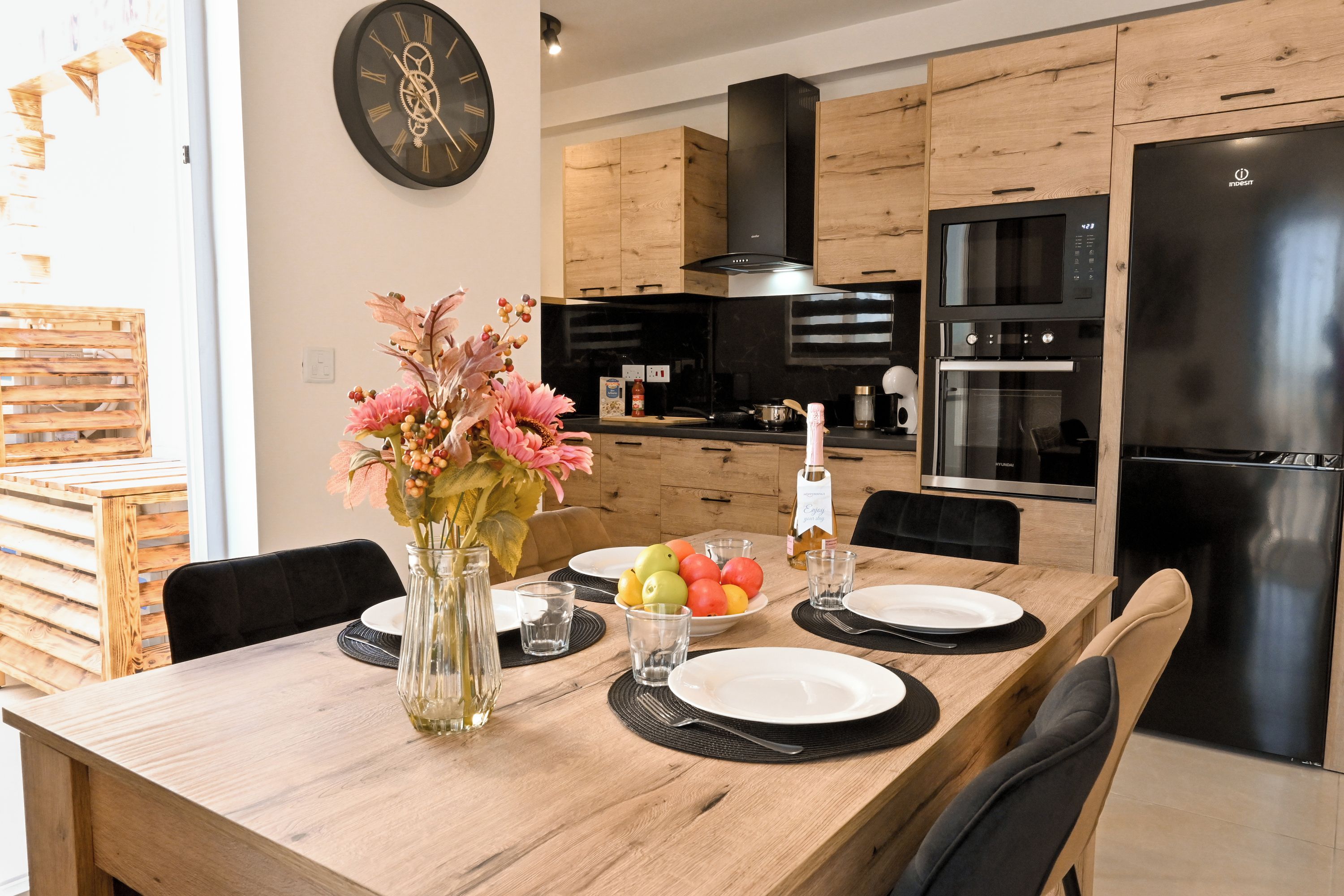 A modern kitchen with wooden cabinets, a black stove, and a stainless steel refrigerator.