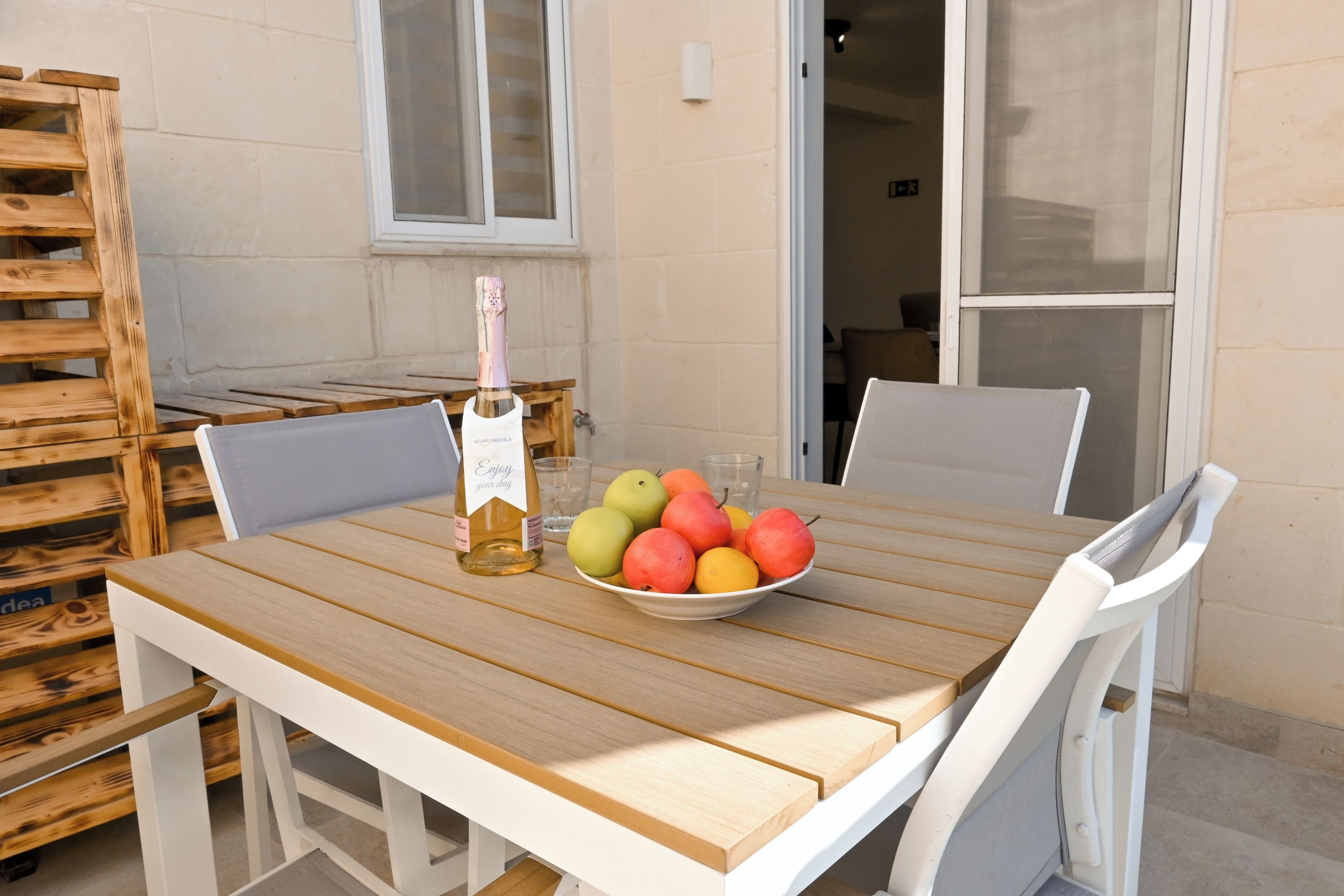 Una mesa de madera con un cuenco de fruta y una botella de champán.