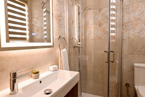 Un baño con cabina de ducha de vidrio, un lavabo con grifo y un inodoro.