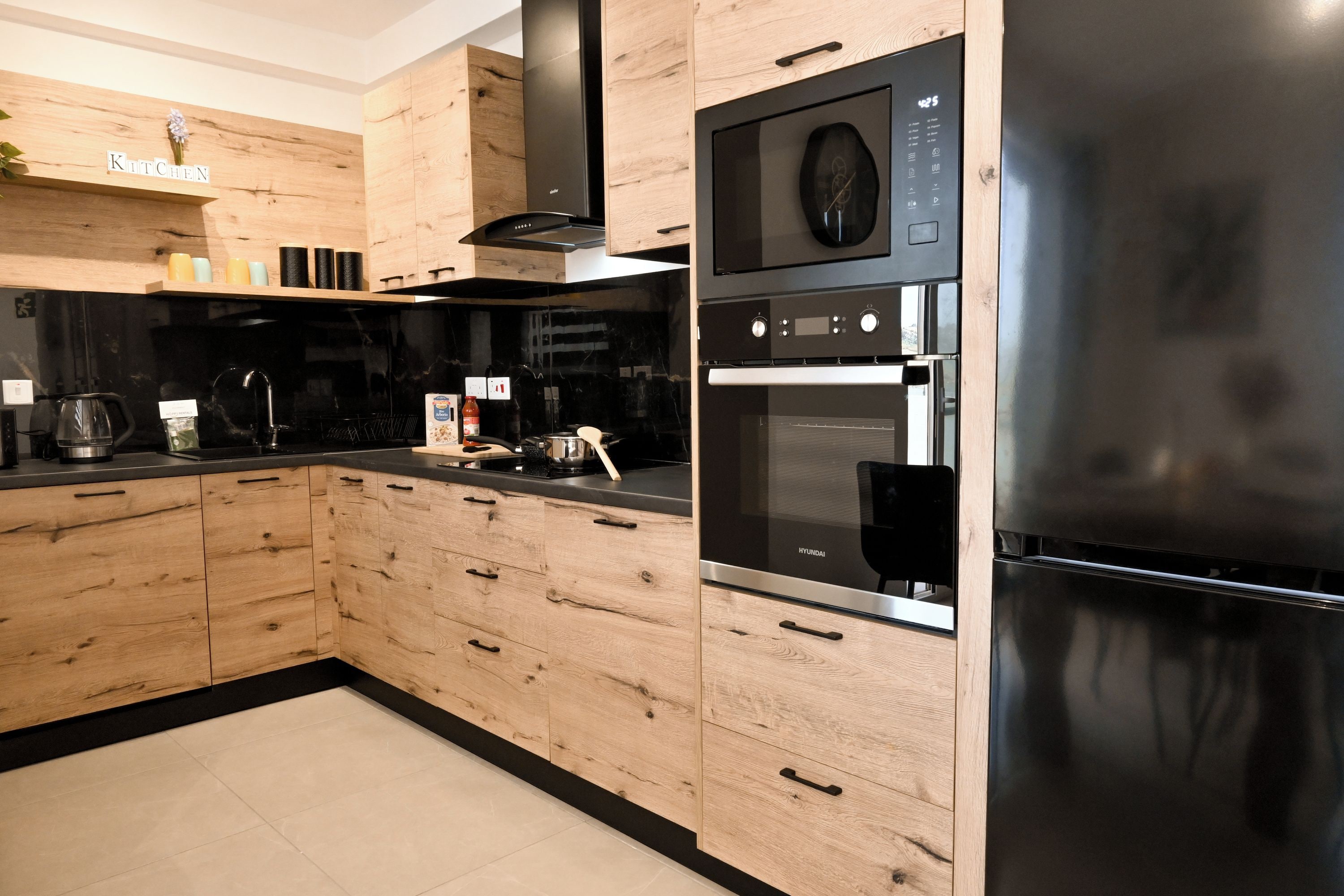 A modern kitchen with wooden cabinets, a stainless steel refrigerator, and a built-in oven.