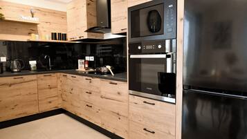 A modern kitchen with wooden cabinets, a stainless steel refrigerator, and a built-in oven.