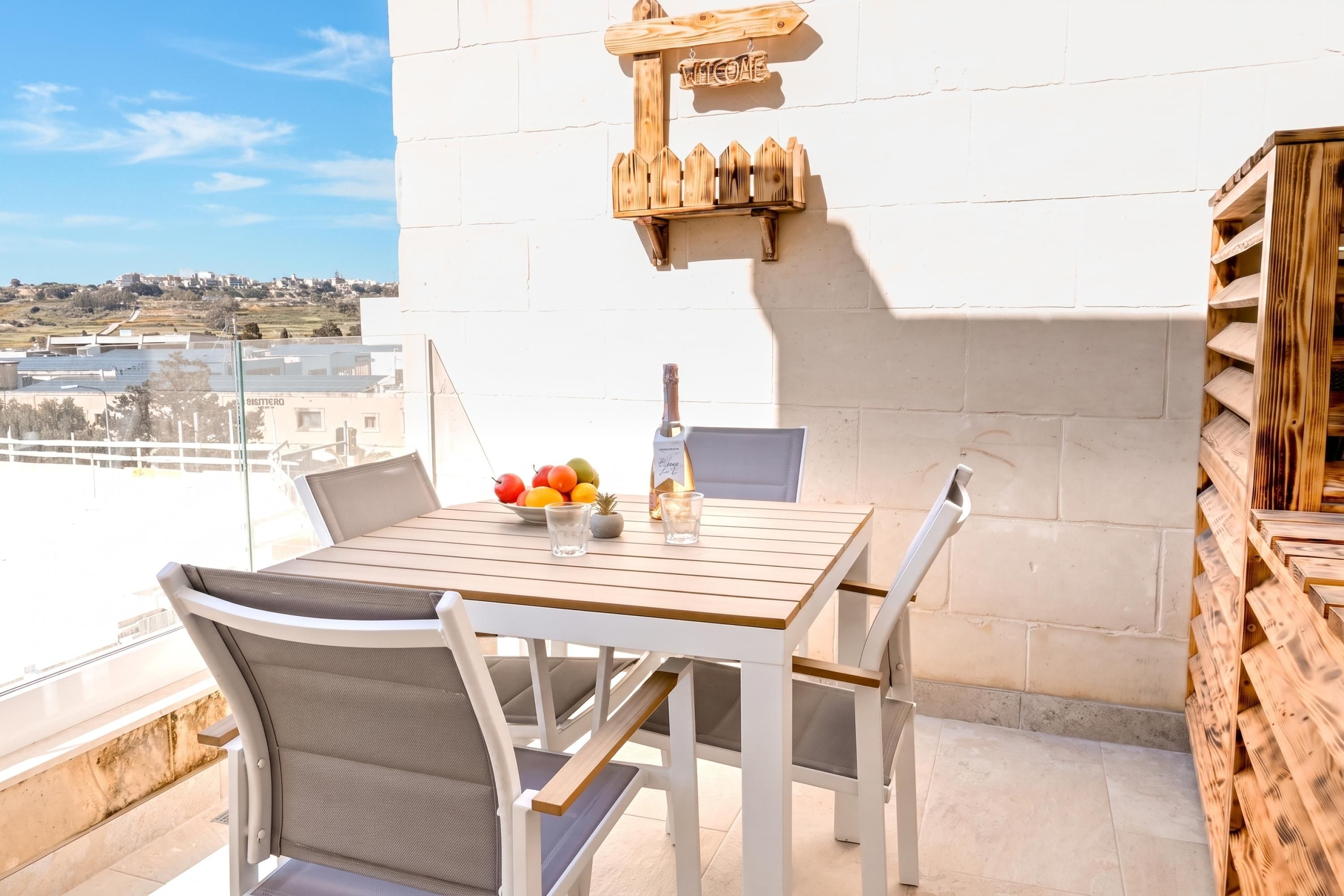 Un balcone con tavolo e sedie in legno e una ciotola di frutta.