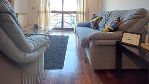 A living room with a sofa, armchair, and a small table with a lamp. - Stay in Porto in an Authentic Neighborhood (Oporto)