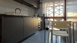A modern kitchen with a microwave, cabinets, a sink, and a chair. - Stay in Porto in an Authentic Neighborhood (Oporto)