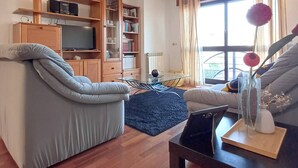 A living room with a sofa, a coffee table, a bookshelf, and a television. - Stay in Porto in an Authentic Neighborhood (Oporto)