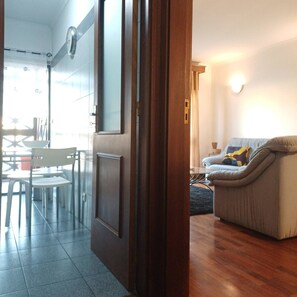 A room with a wooden door, a glass table with chairs, a sofa, and a wall-mounted clock. - Stay in Porto in an Authentic Neighborhood (Oporto)