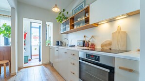 A modern kitchen with white cabinets, a built-in oven, a microwave, and a wooden cutting board. - Charming retreat near Boavista with elevator (Oporto)