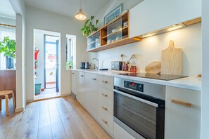 Une cuisine moderne avec des armoires blanches, un four encastré, un four à micro-ondes et une planche à découper en bois.