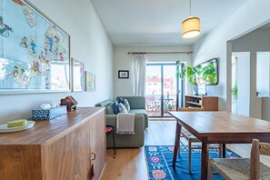 Un salon moderne avec une table à manger en bois, un canapé vert et une grande carte du monde accrochée au mur.