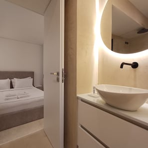 A hotel room with a bed, a bathroom with a large mirror and a vessel sink. - Porto Luxury Downtown Apartment & Garage (Oporto)