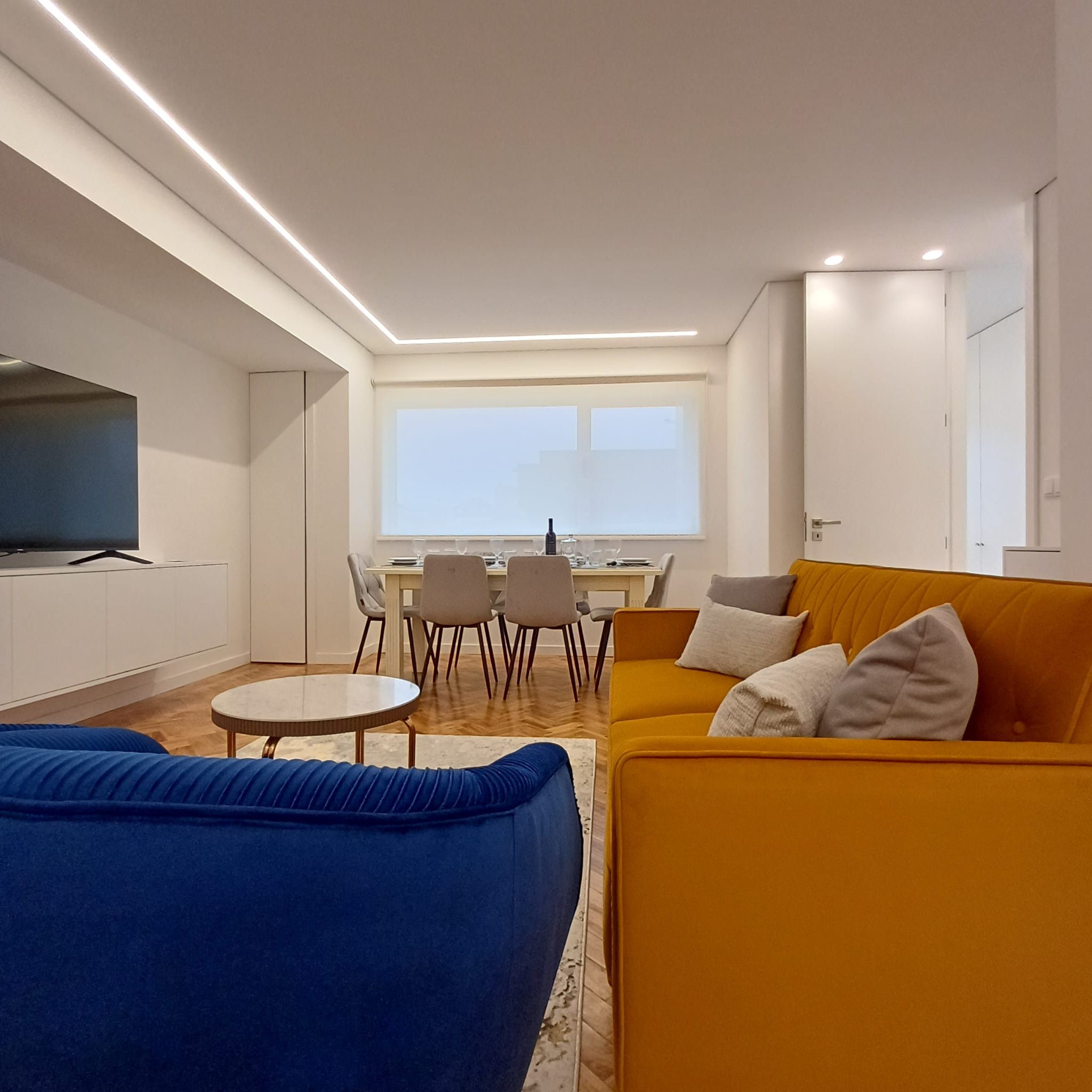 Ein modernes Wohnzimmer mit einer Couch, einem Fernseher und einem Essbereich.