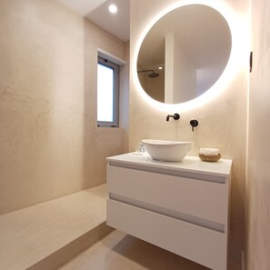 A modern bathroom with a round mirror, a white sink, and a small window. - Porto Luxury Downtown Apartment & Garage (Oporto)