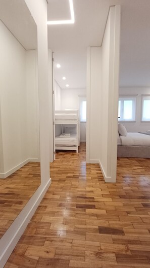 A spacious room with a wooden floor, a bunk bed, and a sofa. - Porto Luxury Downtown Apartment & Garage (Oporto)