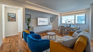 A modern living room with a sofa, chairs, a TV, and a dining area. - Porto Luxury Downtown Apartment & Garage (Oporto)