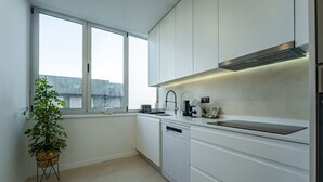 A modern kitchen with white cabinets, a dishwasher, a sink, and a window. - Porto Luxury Downtown Apartment & Garage (Oporto)