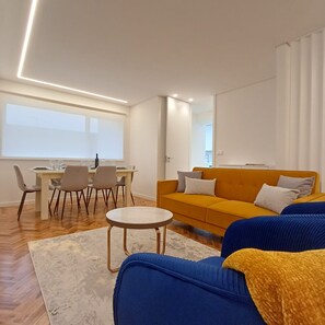A modern living room with a sofa, a dining table, and chairs. - Porto Luxury Downtown Apartment & Garage (Oporto)