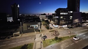 A nighttime cityscape with illuminated buildings, a crosswalk, and a parking lot. - Porto Luxury Downtown Apartment & Garage (Oporto)