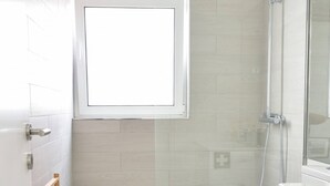 A modern bathroom with a shower, toilet, and a window. - Typical Quarter Nest (Oporto)