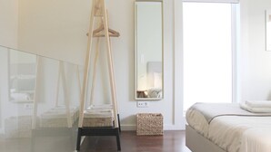 A bedroom with a bed, a standing mirror, a wooden easel, and a wicker basket. - Typical Quarter Nest (Oporto)