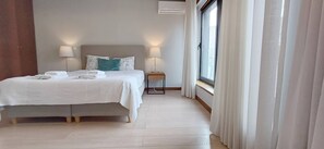 Ein Hotelzimmer mit einem Bett, zwei Nachttischlampen, einem Nachttisch und einem Fenster mit Vorhängen.
