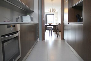 Eine moderne Küche mit Edelstahlgeräten, ein Essbereich mit Holzkästen und Blick ins Freie.