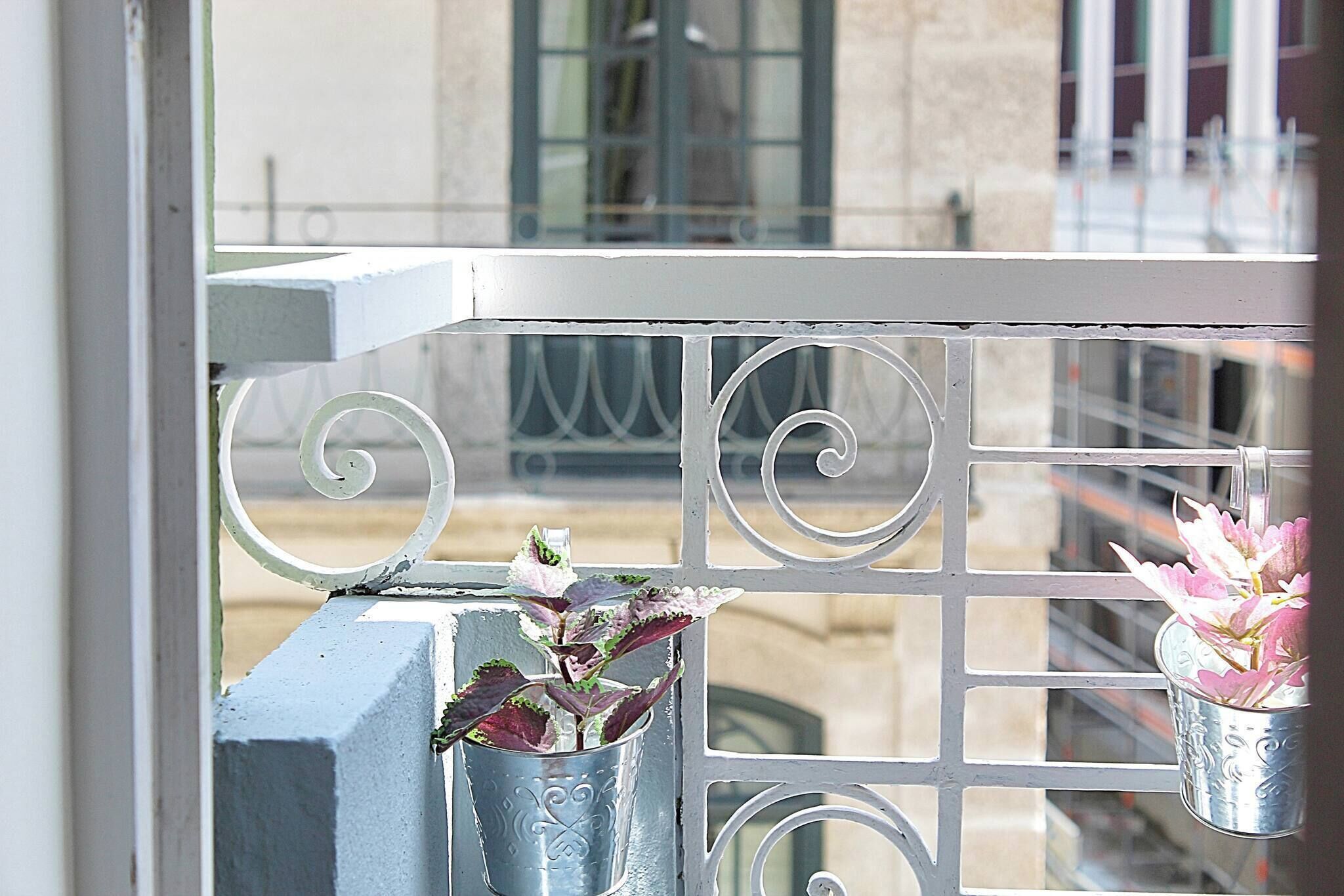 Ein Balkon mit Metallgeländern und zwei Blumenampeln.