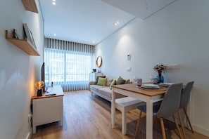 A modern living room with a sofa, dining table, and a small white cabinet. - Antas Park Concept Lifestyle With Pool (Oporto)