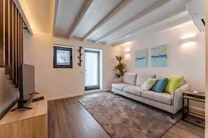 Una sala de estar moderna con un sofá, un televisor y una escalera.
