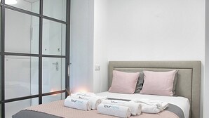 A hotel room with a bed, a large window, and a bedside table. - Arrábida Luxury Studio (Vila Nova de Gaia)