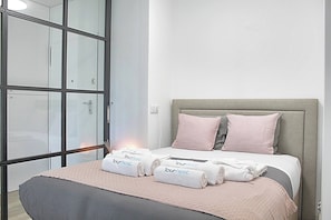 Ein Hotelzimmer mit einem Bett, einem großen Fenster und einem Nachttisch.