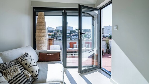 Una sala de estar moderna con un sofá, un ventanal y vista a la ciudad.