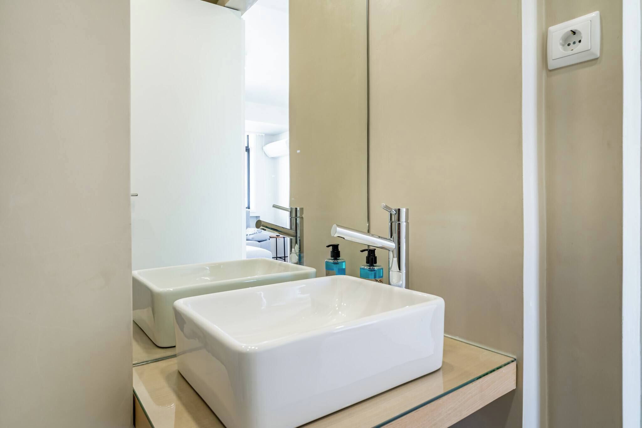 Un bagno con due lavandini, uno specchio e un interruttore a muro.
