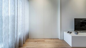 Een moderne kamer met een houten vloer, een witte wand en een televisie op een witte standaard.